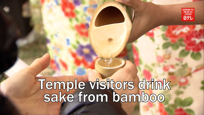 Temple visitors drink sake from bamboo 